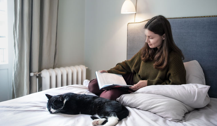 Woman reading in bed with her cat