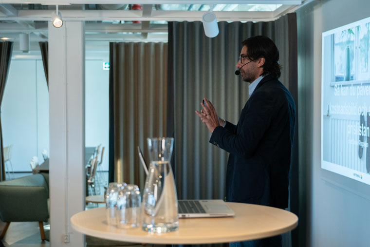 Man i kostym presenterar innehåll framför en storbildsskärm