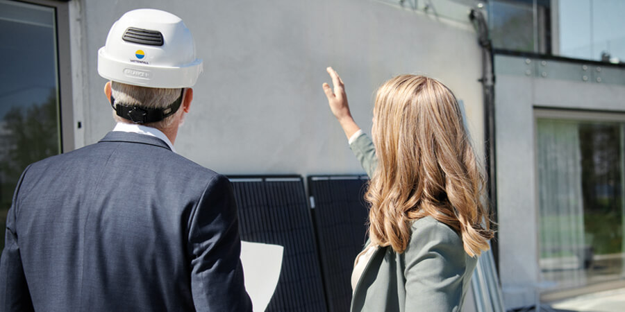 Man och kvinna som står framför ett hus och diskuterar solpaneler