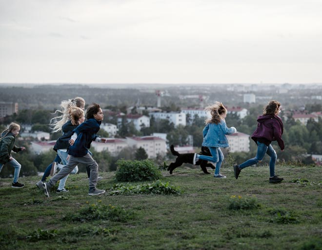Barn springer på en kulle