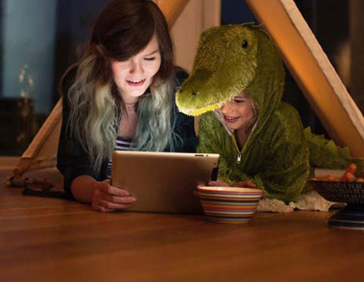 Två barn ligger på golvet med en surfplatta