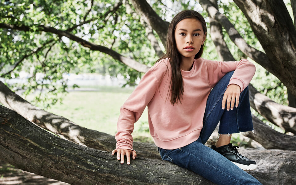 Flicka som sitter i skuggan av ett träd