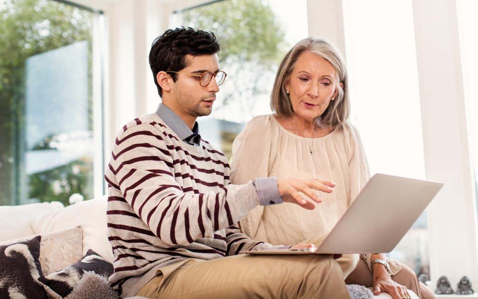 Man och kvinna som sitter i en soffa och tittar på en laptop