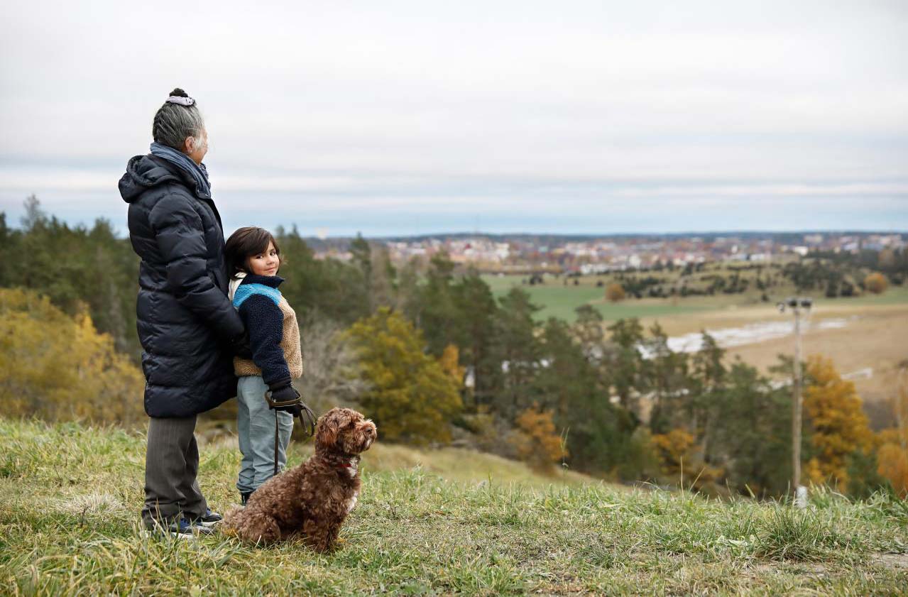 Två personer med hund blickar ut över ett landskap