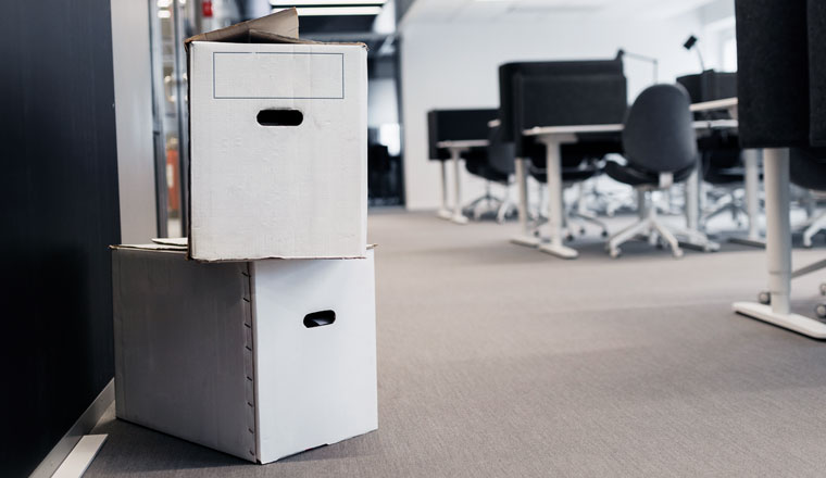 Flyttkartonger som står på ett golv i ett öppet kontorslandskap