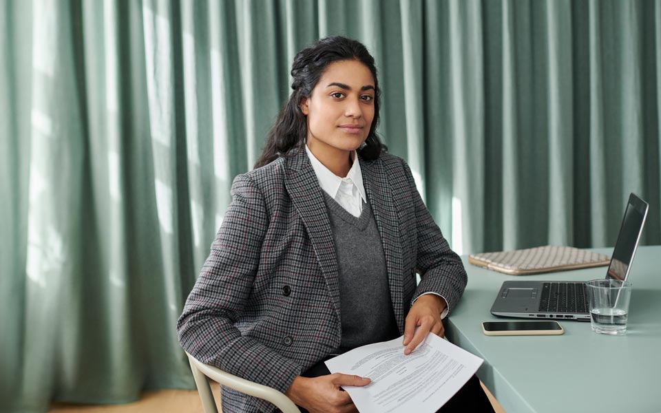 Kvinna som sitter vid ett skrivbord och håller i papper