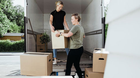 två kvinnor lastar flyttkartonger i en lastbil