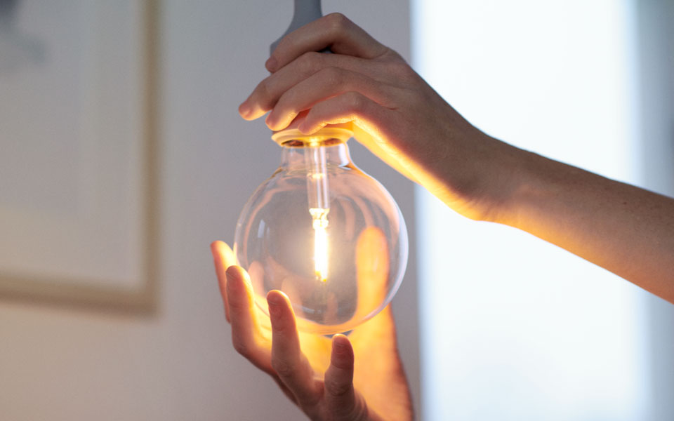 Närbild på händer som skruvar i en lampa