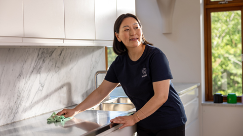 Kvinna står i ett kök och städar