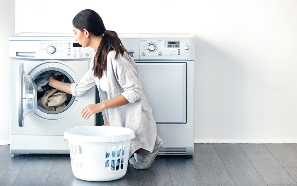 Kvinna som lägger in kläder i en tvättmaskin