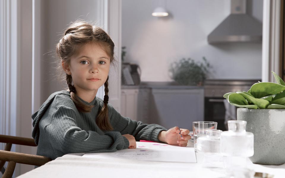 Flicka som sitter vid ett bord och gör läxor