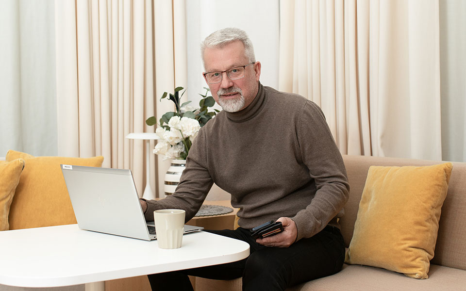 Anders Rydberg sitter i en soffa med mobiltelefonen i handen.