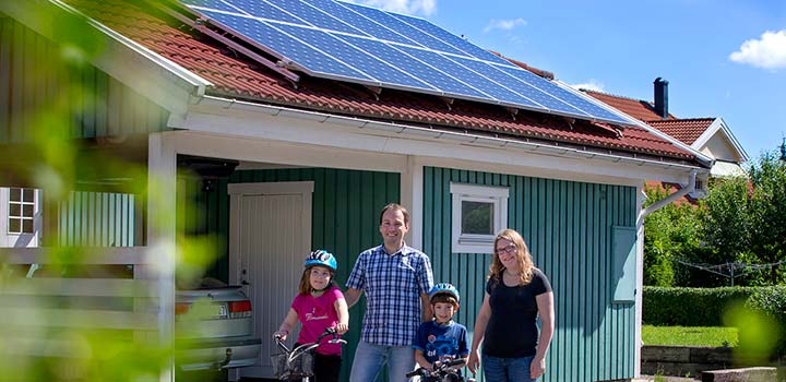 Familjen Parrat framför sitt garage som har solceller på taket