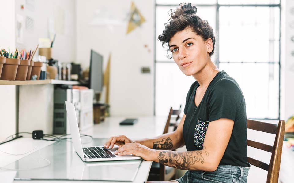 Kvinna som sitter vid en skrivbord och arbetar med en laptop