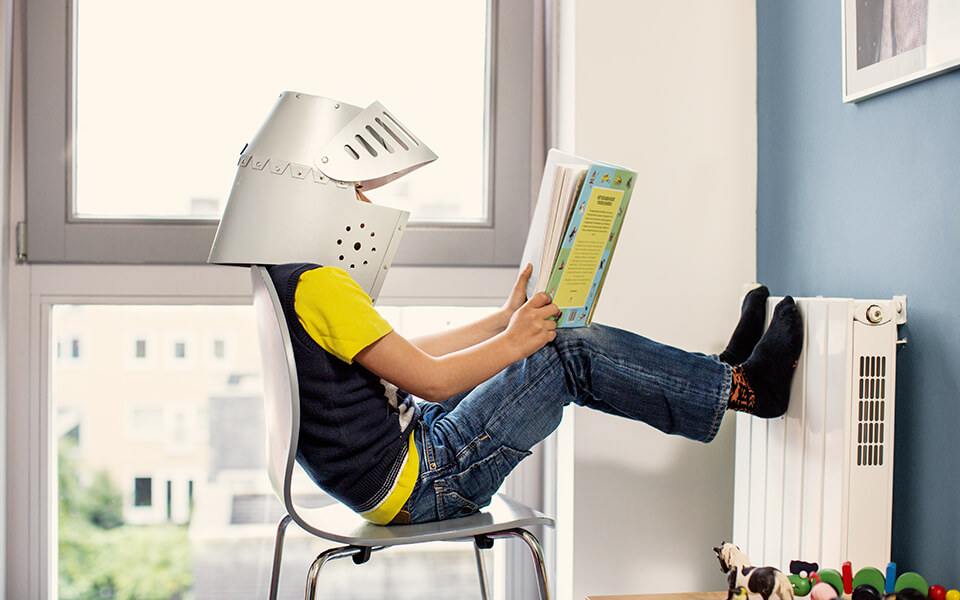 Pojke som värmer fötterna på ett element