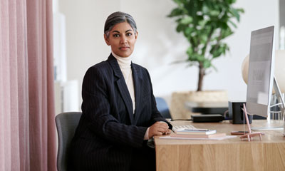 Kvinna som sitter vid ett skrivbord framför en dator