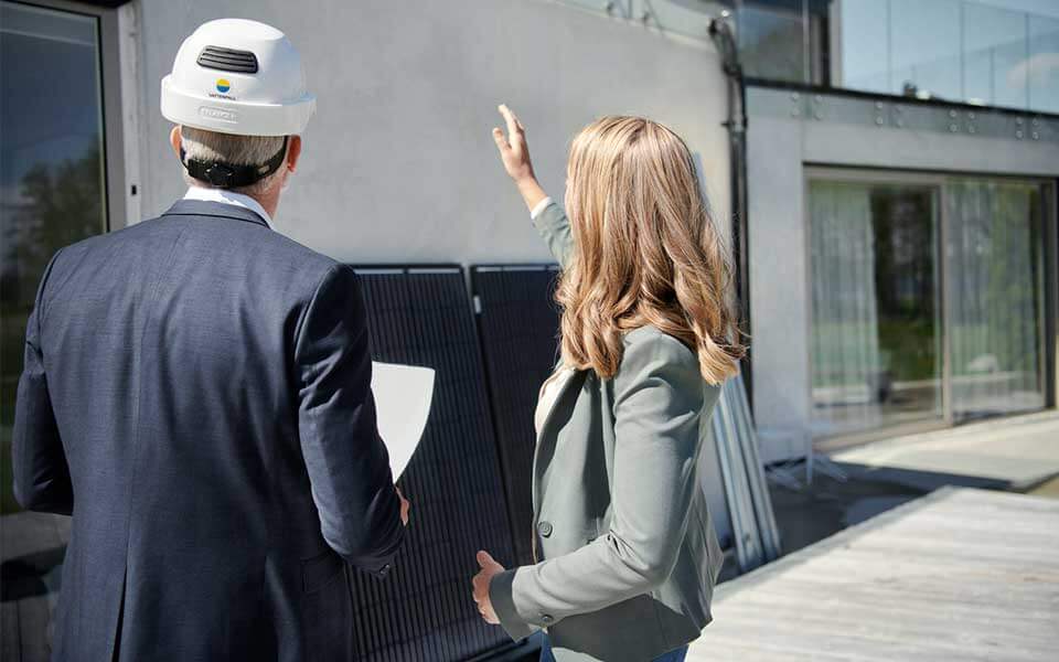 Man och kvinna står framför ett hus och planerar solcellsanläggning