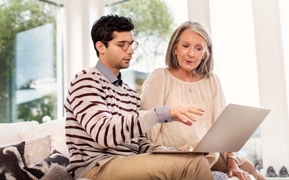 En man och kvinna som sitter i en soffa och tittar på en laptopskärm