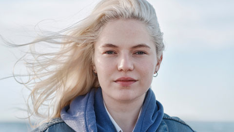 Närbild på ung kvinna vars ljusa hår blåser i vinden