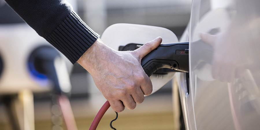 Närbild på en hand som laddar en elbil