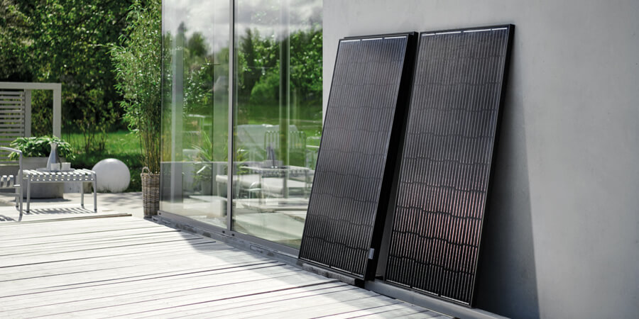 Solpaneler som står lutade mot en husvägg