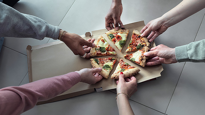 Händer som tar för sig av varsin bit flyttpizza
