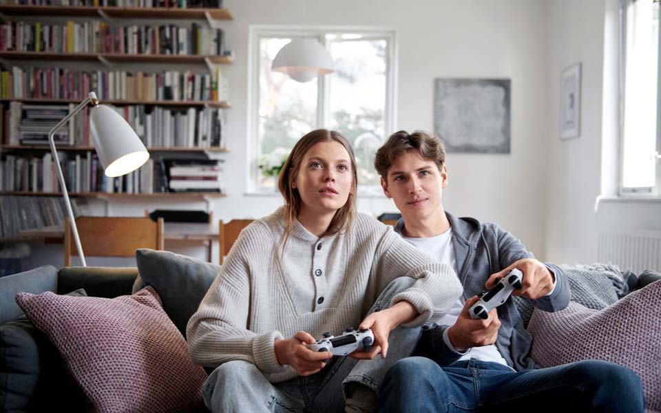 Ungt par som sitter i en soffa och spelar tv-spel