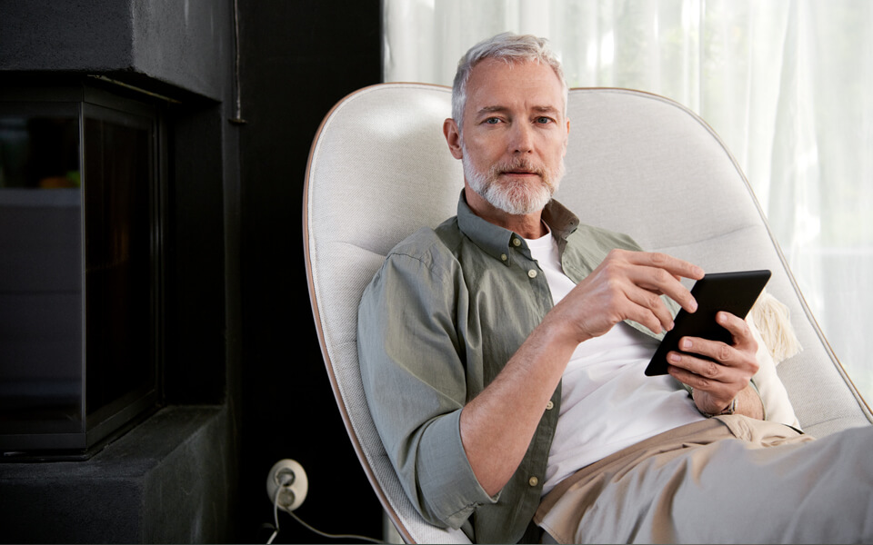 Man som sitter i en fåtölj och tittar på en läsplatta