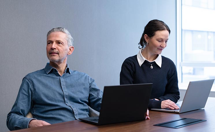 En kivnna och två män i ett konferensrum
