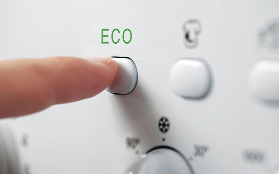 Finger som trycker igång ekoprogrammet på en tvättmaskin.