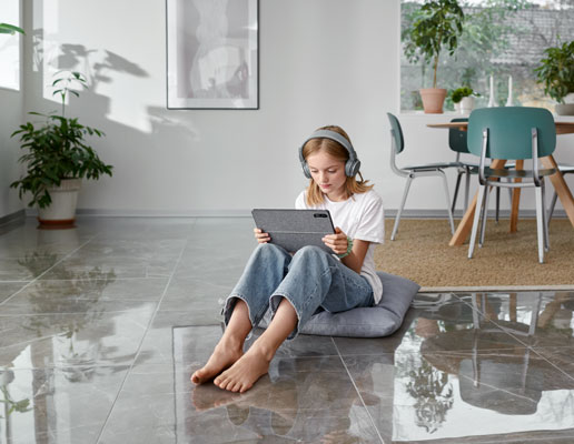 Flicka sitter på golvet med en läsplatta