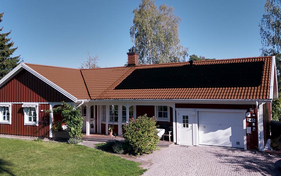 Rött bostadshus med vita knutar och solpaneler på taket.