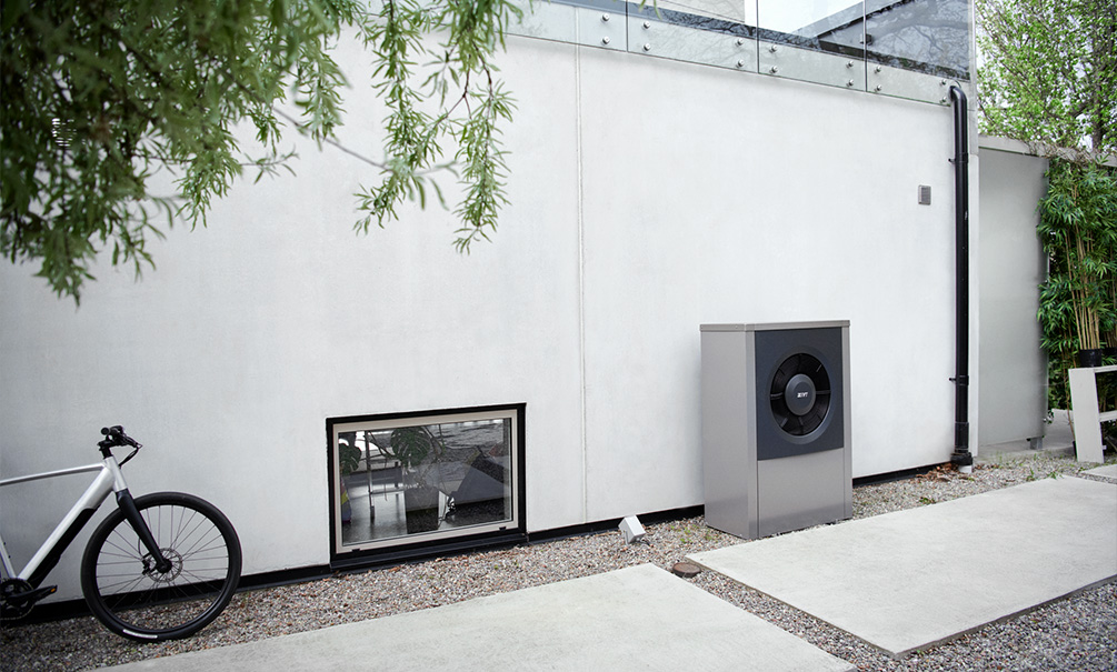 Modern vit villa med en luft-vattenvärmepump monterad på utsidan