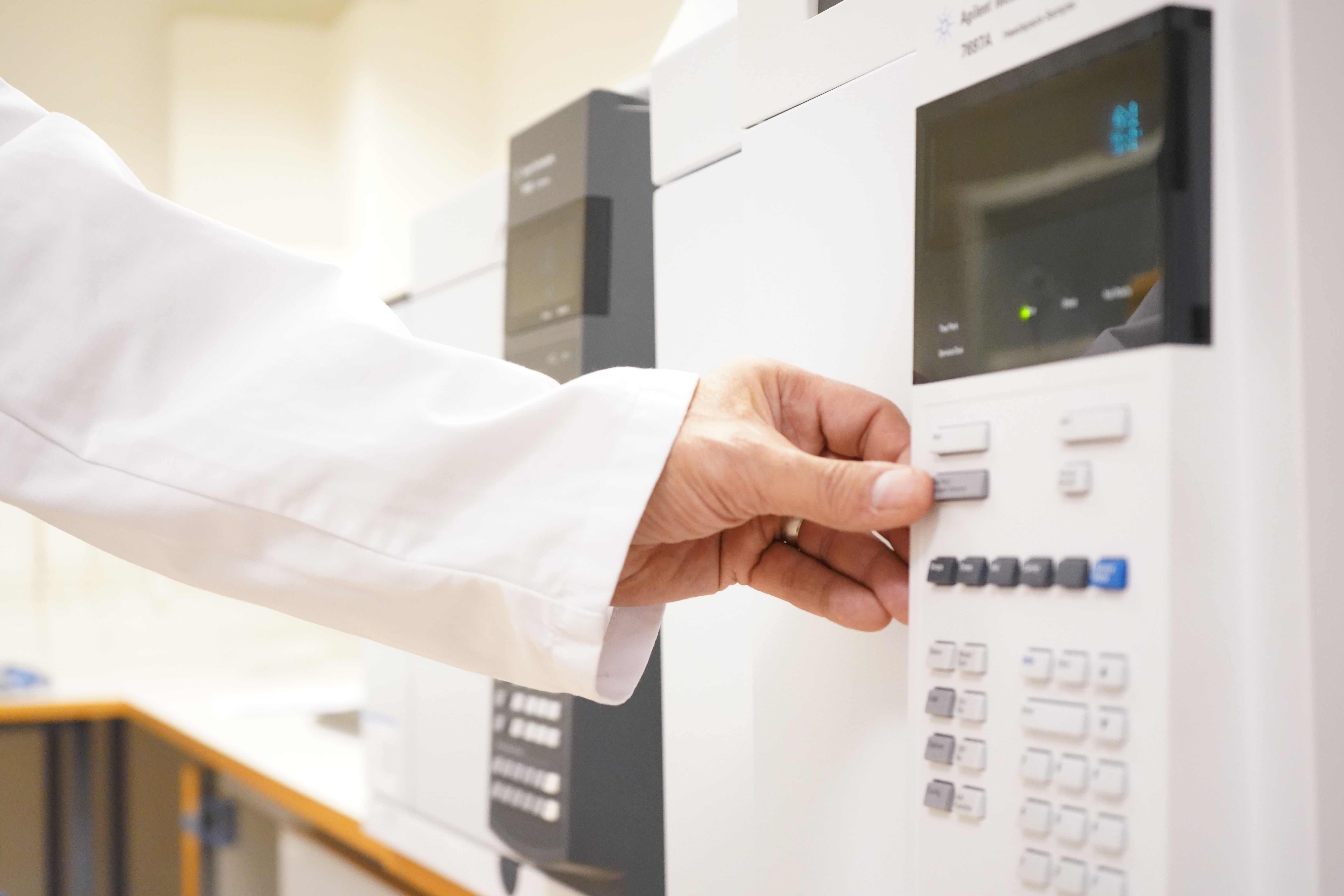 En hand som trycker på en maskin i ett laboratorium