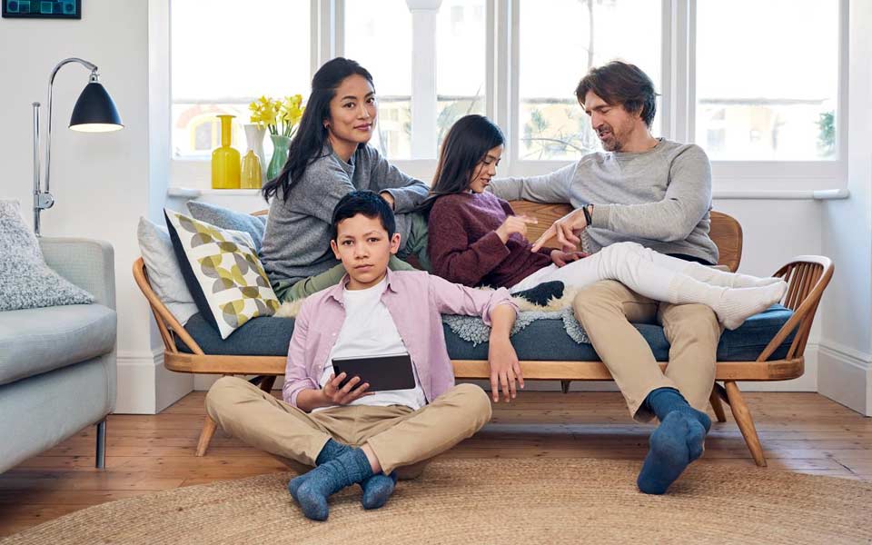 Familj på fyra personer som sitter i en soffa