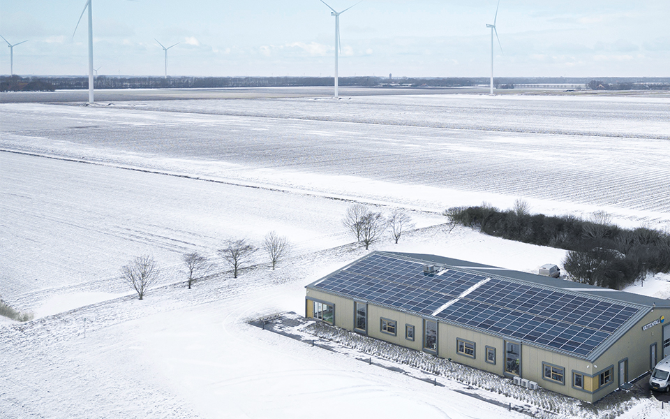 Solceller på en byggnad i ett snöigt, öppet landskap