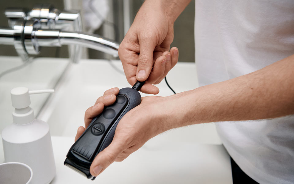 Man som håller en rakapparat ovanför ett handfat