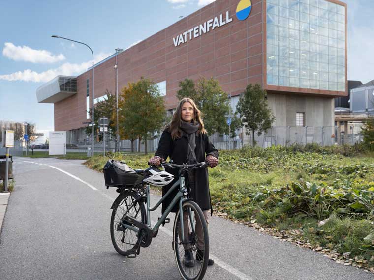 Kvinna med cykel utanför ett av Vattenfalls värmeverk