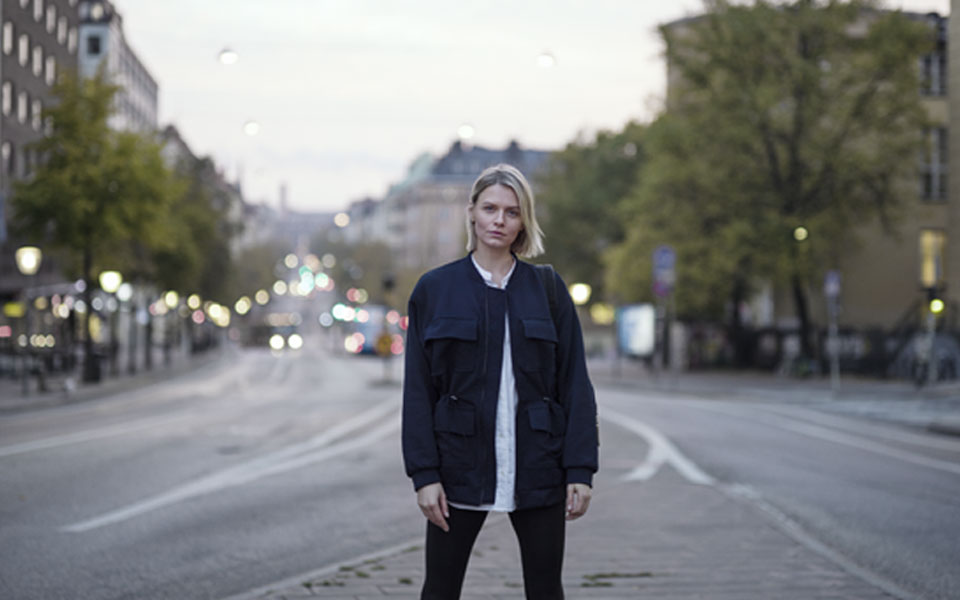 Svartklädd kvinna som står utomhus på en trottoar