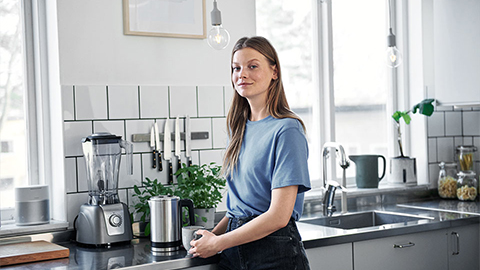 Ung kvinna med en kopp vid en diskbänk