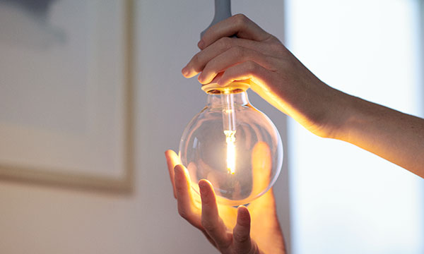 Händer som skruvar i en glödlampa