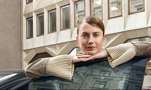 Ung kvinna som lutar sig över en öppen bildörr