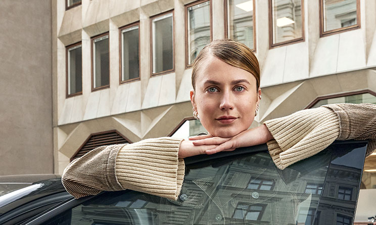 Ung kvinna som lutar sig mot en öppen bildörr