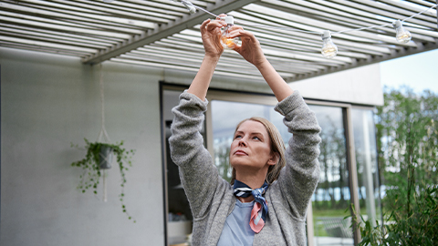 Kvinna på terass fixar ljusslinga