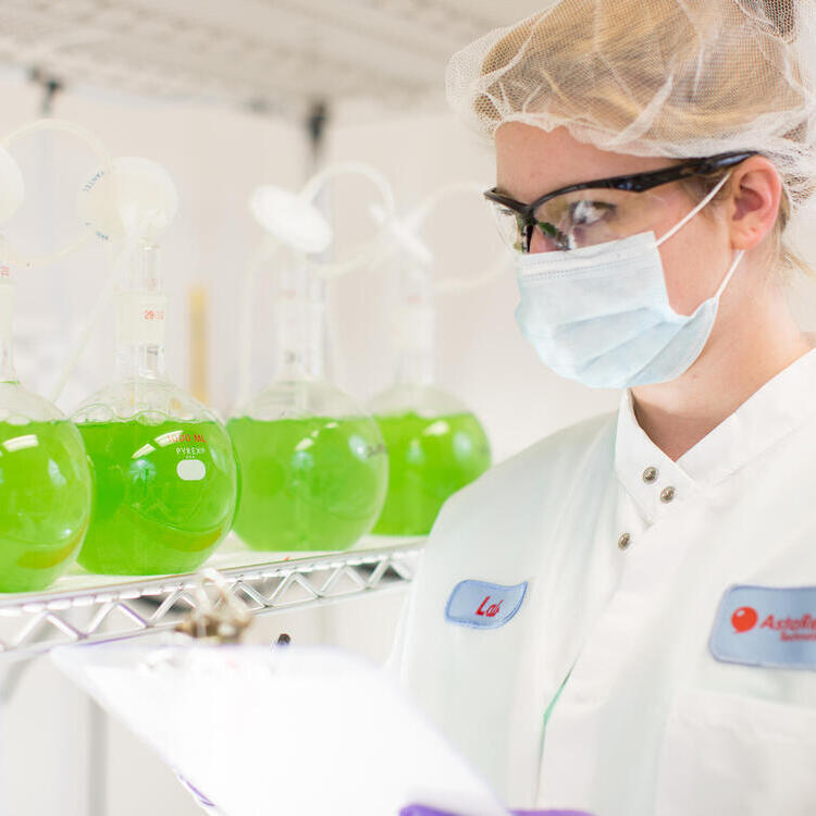 En kvinna med munskydd står i labbet.