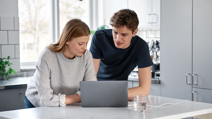 Två unga vuxna vid en dator i ett kök