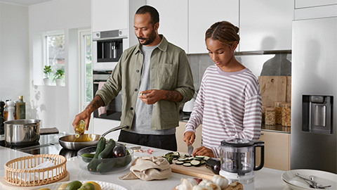 Man och tonåring fixar mat i köket.