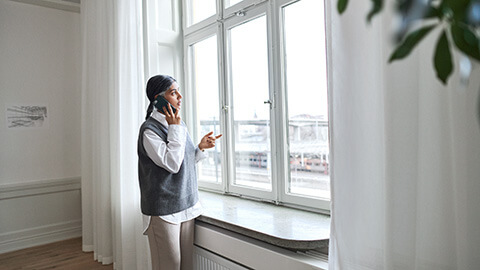 En kvinna står och tittar ut från fönstret.