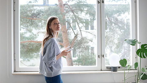 Kvinna som står bredvid ett fönster och pratar i en mobiltelefon