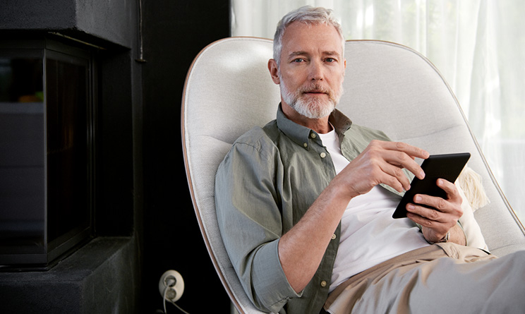 Man i fåtölj som tittar på sin telefon